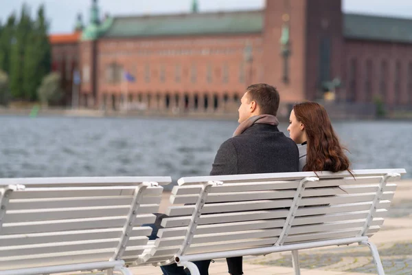 Casal jovem relaxante em um banco desfrutando do pôr do sol — Fotografia de Stock