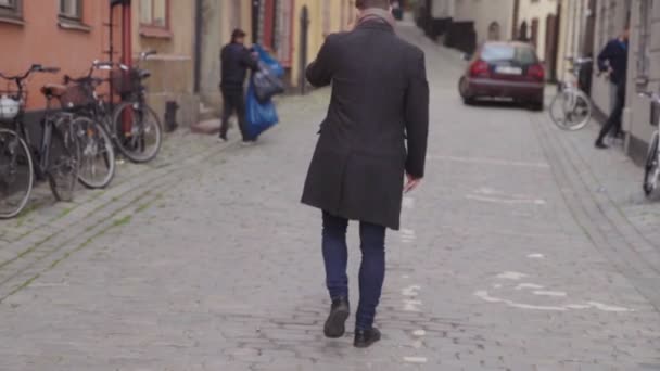 Ung man i ytterrock vänder en promenad bort — Stockvideo