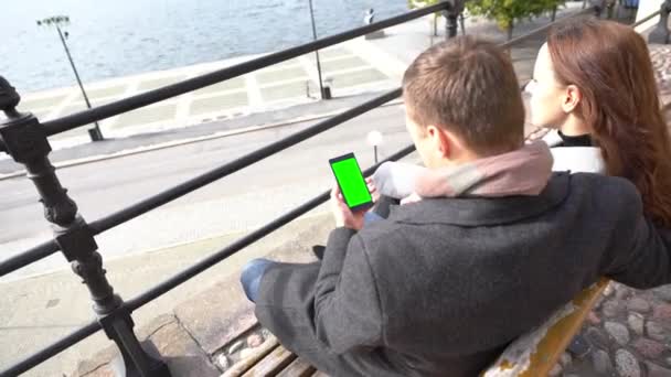 Junges Paar sitzt auf einer Bank am Wasser — Stockvideo