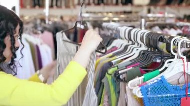 Çekici genç bir kadın çizgili bir bluz seçiyor.