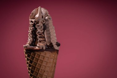 Dondurmalı ve çikolatalı gofretlerle süslenmiş, kestane rengi arka plan üzerine sos serpiştirilmiş.