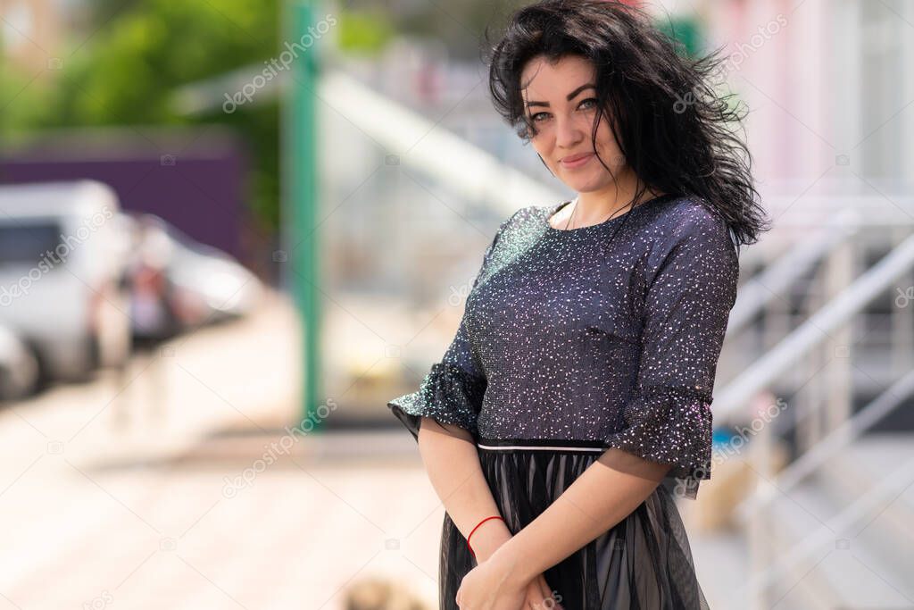 Friendly happy woman with a lovely warm smile standing in town on a windy day with her hair blowing around her face smiling at the camera