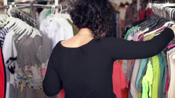 Mujer joven seleccionando ropa en una boutique — Vídeo de stock