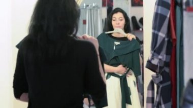 Genç bir kadın bir mağazada elbise tutuyor.