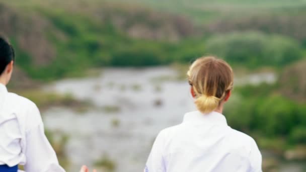 Duas mulheres meditando juntas com vista para um vale — Vídeo de Stock