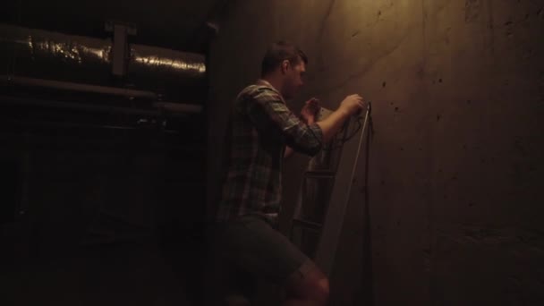 Hombre subiendo una escalera para alcanzar una bombilla — Vídeo de stock