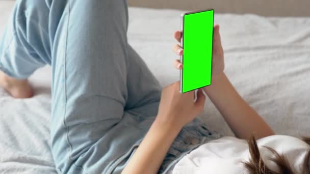 Mladá žena relaxuje na posteli se svým mobilním — Stock video