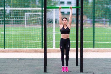 Açık hava spor salonunda paralel bir bar ve spor alanında spor yapan sağlıklı ve zinde bir kadın.