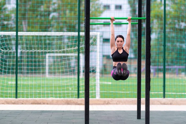 Fit toned young woman working out on parallel bars at an outdoor sports facility in town in a health and fitness or active lifestyle concept with copyspace