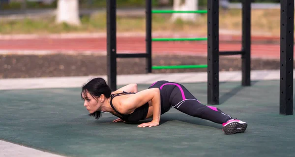 年轻女性在做瑜伽运动时 把身体和健康或者积极的生活方式的概念放在室外体育馆里 她的姿势也会发生分裂 — 图库照片