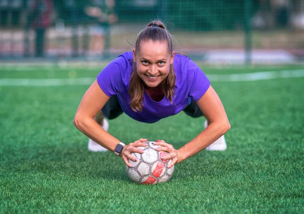Młoda Kobieta Robi Pompki Pomocą Piłki Patrząc Górę Aby Uśmiechać — Zdjęcie stockowe
