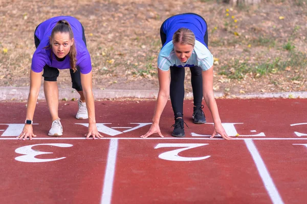 Yarışa Hazırlanan Iki Genç Kadın Bir Spor Pistinde Başlangıç Pozisyonunda — Stok fotoğraf