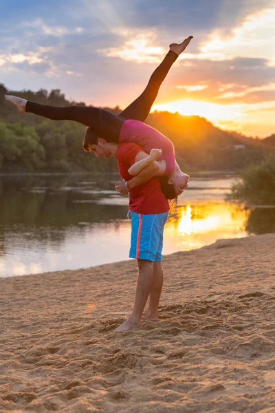 Sportowa Para Uprawiająca Jogę Akrobatyczną Zachodzie Słońca Plaży Pozycji Zespołowej — Zdjęcie stockowe