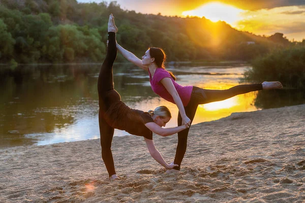 Dwie Kobiety Uprawiające Zsynchronizowaną Jogę Akrobatyczną Piaszczystej Plaży Zachodzie Słońca — Zdjęcie stockowe