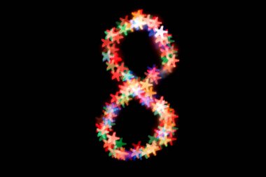 Şekil 8 siyah bir arka plan üzerinde renkli bir bokeh oluşturulmuş. Dünya Kadınlar günü. 8 Mart.