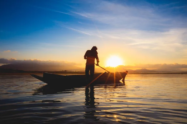 剪影渔夫站立在小船在日出期间 — 图库照片