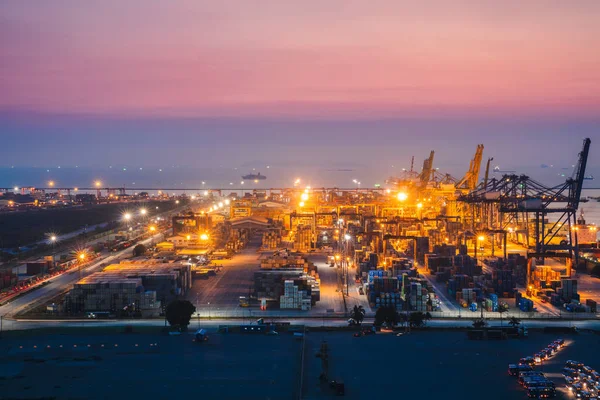コンテナー貨物貨物船造船所でクレーン橋ロジスティック インポート エクスポート背景の夕暮れ時に作業 — ストック写真