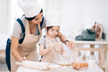 Anne ve kızı mutfakta birlikte merdane kullanıyorlar.