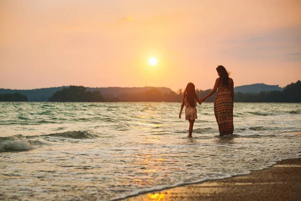 Mor och dotter som promenerar på stranden med solnedgång — Stockfoto