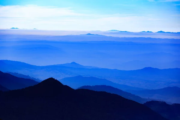 Pasmo Górskie Widocznymi Sylwetkami Przez Poranną Niebieską Mgłę — Zdjęcie stockowe
