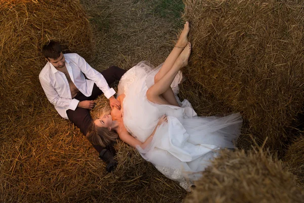 新郎抚摸新娘的头, 而她躺在干草上 免版税图库照片
