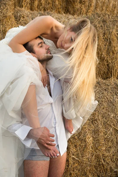 La sposa abbraccia teneramente lo sposo con i piedi e si china verso di lui — Foto Stock