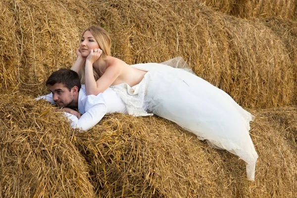 La novia abraza tiernamente al novio con los pies y se inclina hacia él —  Fotos de Stock