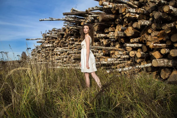 Young beautiful girl on a background of sawn trees — Stock Photo, Image