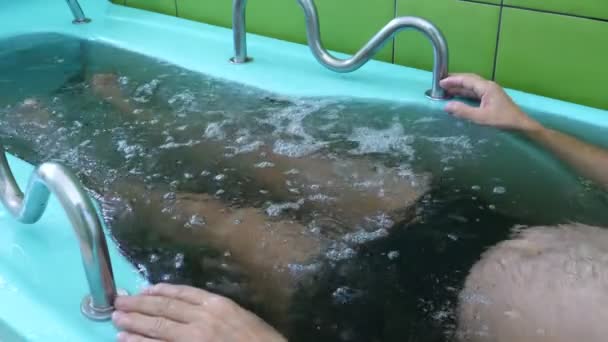 レクリエーションのスパリゾートで男をハーブとバブルのミネラル水でジャグジー浴槽で横になっているとリラックス — ストック動画
