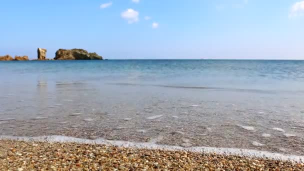 附近的平坦的海滩砾石洗地中海平静的蓝色水 美丽的克里特岛海滨景观与岩石在地平线上 — 图库视频影像