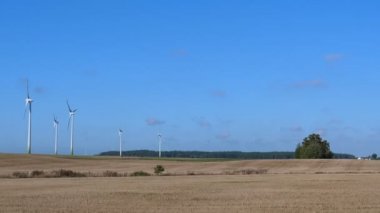 Kırsal kesimde seyahat araba yan pencere görünümü. Rüzgar Çiftliği türbinleri anız alan arkasında mavi gökyüzü karşı iplik