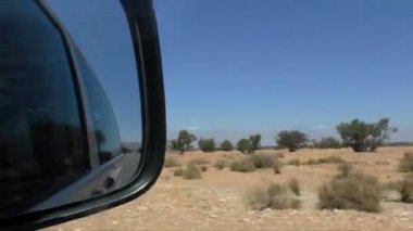 Fas'ta araba ile seyahat. Hareketli araba yan dikiz aynası üzerinde odaklanın. Bazı ağaçlar ve yüksek Atlas dağ uzakta, Kuru Afrika yatay