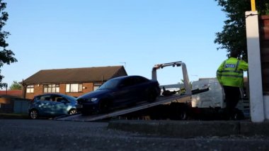 SALFORD, MANCHESTER, İngiltere - Mayıs 2020: İngiliz polis memuru, konut alanındaki küçük bir otoparkta aracın taşınmasını gözlemlerken radyodan konuşuyor.