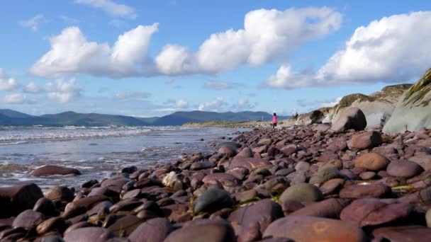 爱尔兰共和国大西洋海岸的Rossbeigh海滩在美丽的阳光明媚的日子里 男人在卵石沙滩上拍下女人的照片 — 图库视频影像