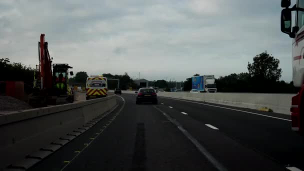 ENGLAND, UNITED KINGDOM - SEPTEMBER, 2020: Car windshield view driving M6 motorway early in the morning and passing roadworks machinery and workers, speed restrictions apply. — Stock Footage England United Kingdom September 2020 Car Windshield View Driving Motorway Video Clip