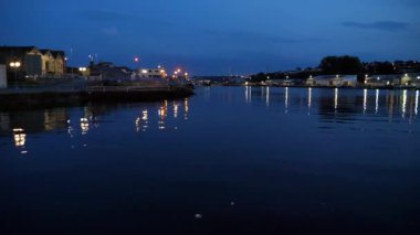Kasaba ışıkları gece Galler Milford Haven marinasının koyu mavi dalgalı suyuna yansıyor..