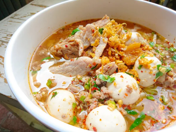 Closeup Spicy TOM YAM Pork Noodles Soup with Pork Balls, chilly pasted and lime juice / Noodles in Thai spicy tom yum soup with pork