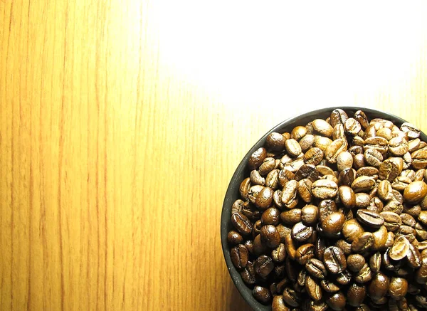 Naturliga Rostad Kaffebönor Isolerade Svart Skål Träbord — Stockfoto