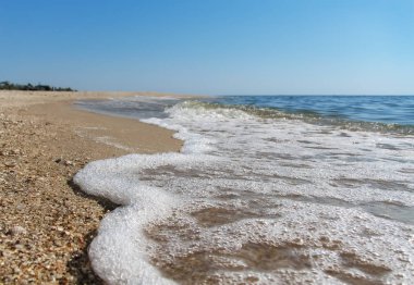 Deniz ve kum kıyısında deniz köpüğü