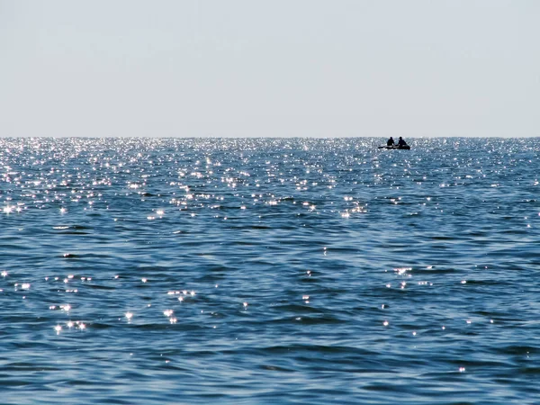 Μια γαλάζια θάλασσα με ήλιο glares και μοναχικό βάρκα Royalty Free Φωτογραφίες Αρχείου