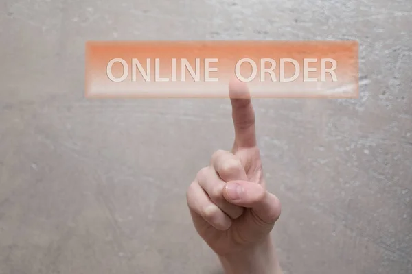 Online order - man finger clicking on transparent orange virtual  interface button on grunge light brown background with copy space for text and image. Online purchasing and selling business concept.