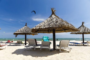 Kumlu plajda güneş tonları ve şezlonglar