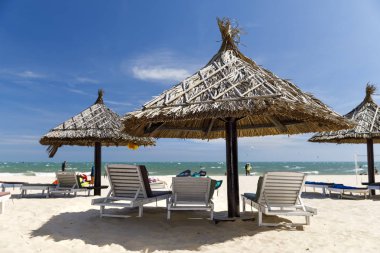 Kumlu plajda güneş tonları ve şezlonglar