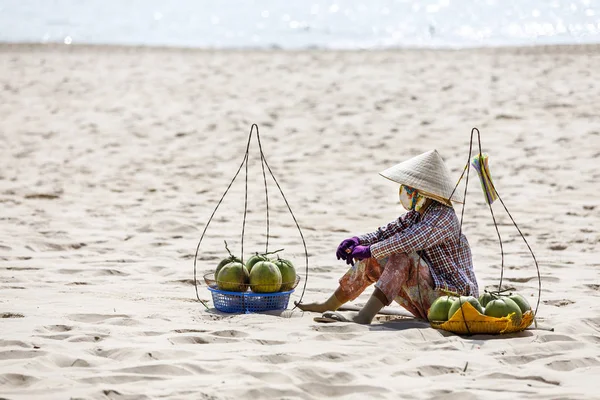 Sprzedawca owoców i napojów siedzieć na piaszczystej plaży w nam Tien, Wietnam — Zdjęcie stockowe