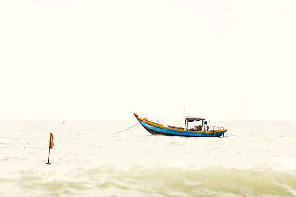 Pescatore con una barca da pesca in legno su un mare in Nam Tien, Vietnam — Foto Stock