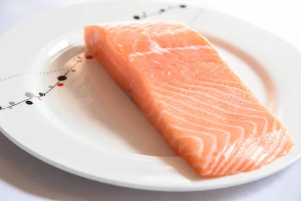 Salmon in white dish on white blackground.