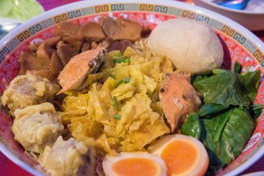 Şehriye veya düz şehriye veya yumurta noodle, yengeç, haşlanmış yumurta, hamur tatlısı, domuz, et topu ve bir kase içinde sebze