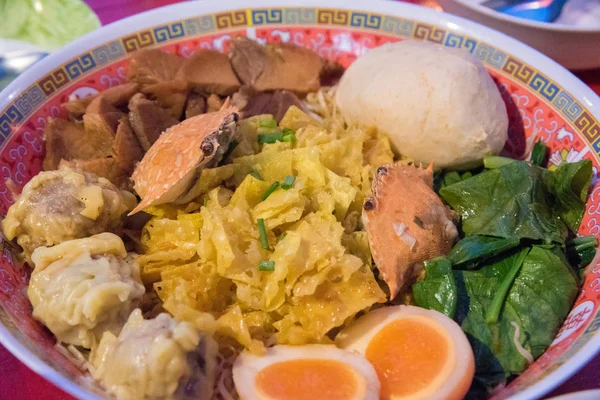 Şehriye veya düz şehriye veya yumurta noodle, yengeç, haşlanmış yumurta, hamur tatlısı, domuz, et topu ve bir kase içinde sebze