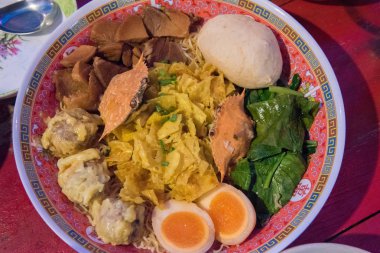 Şehriye veya düz şehriye veya yumurta noodle, yengeç, haşlanmış yumurta, hamur tatlısı, domuz, et topu ve bir kase içinde sebze