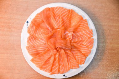 Closeup üstten görünüm beyaz tabak Slided çiğ somon ahşap blackground üzerinde